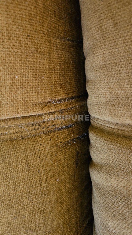 Coussins de canapé en tissu ocre, traînées de points noirs le long d'un pli horizontal